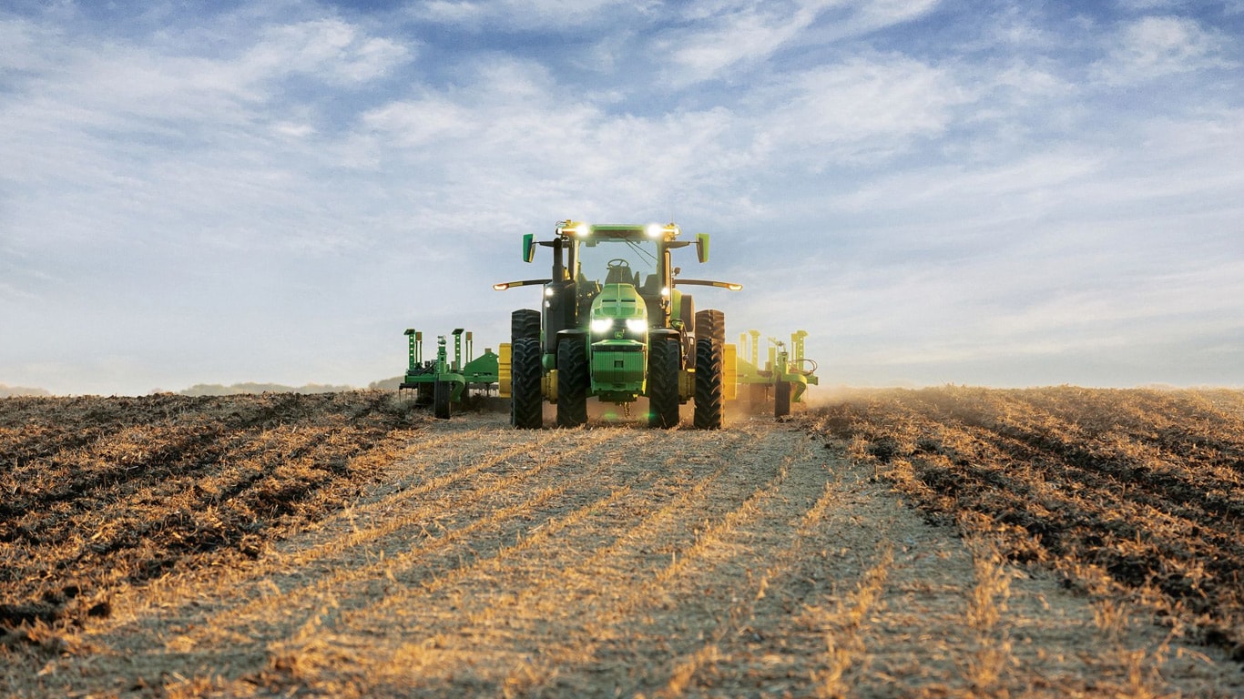 John Deere-ის თვითმართვადი ტრაქტორი, რომელსაც ნიადაგის დასამუშავებელი აღჭურვილობა ღია მინდორში გადააქვს.