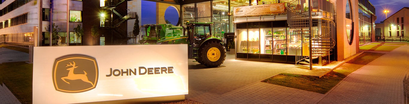 John Deere-ის სათავო შენობის წინა ხედი აუზით და ტირიფის ხეებით წინა პლანზე